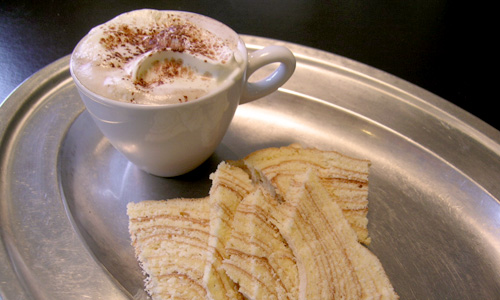 Kaffee und Baumkuchen auf silbernem Tablett